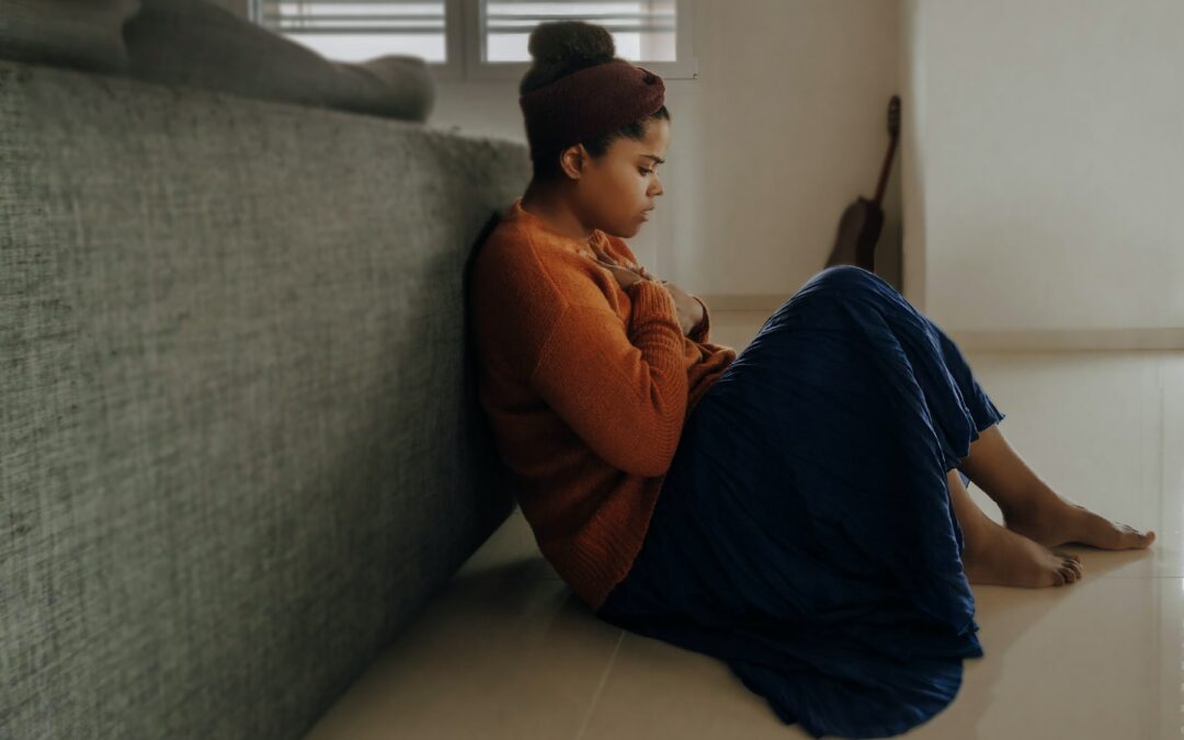 man in orange long sleeve shirt sitting on gray couch